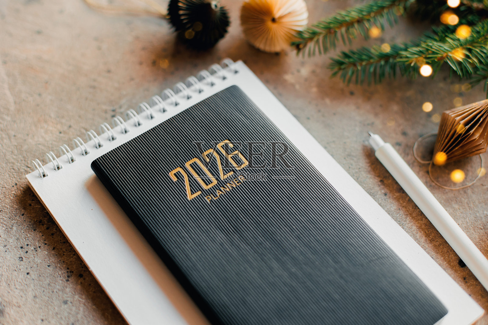 时尚的办公桌布置，配有 2026 年计划本、笔记本、铅笔和桌面上的冷杉树枝照片摄影图片