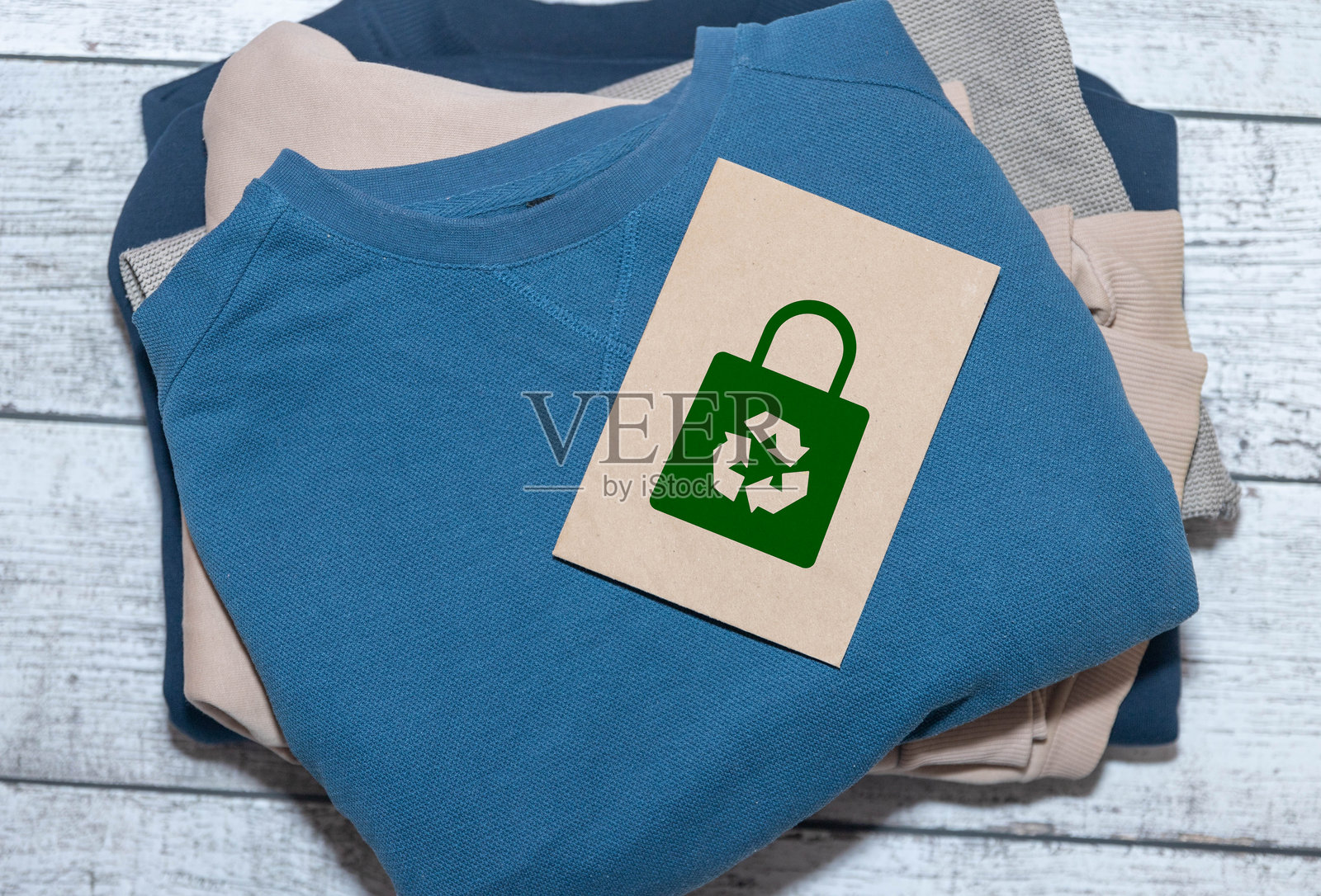 一叠整齐的针织服装，上面贴有100%回收标签。照片摄影图片