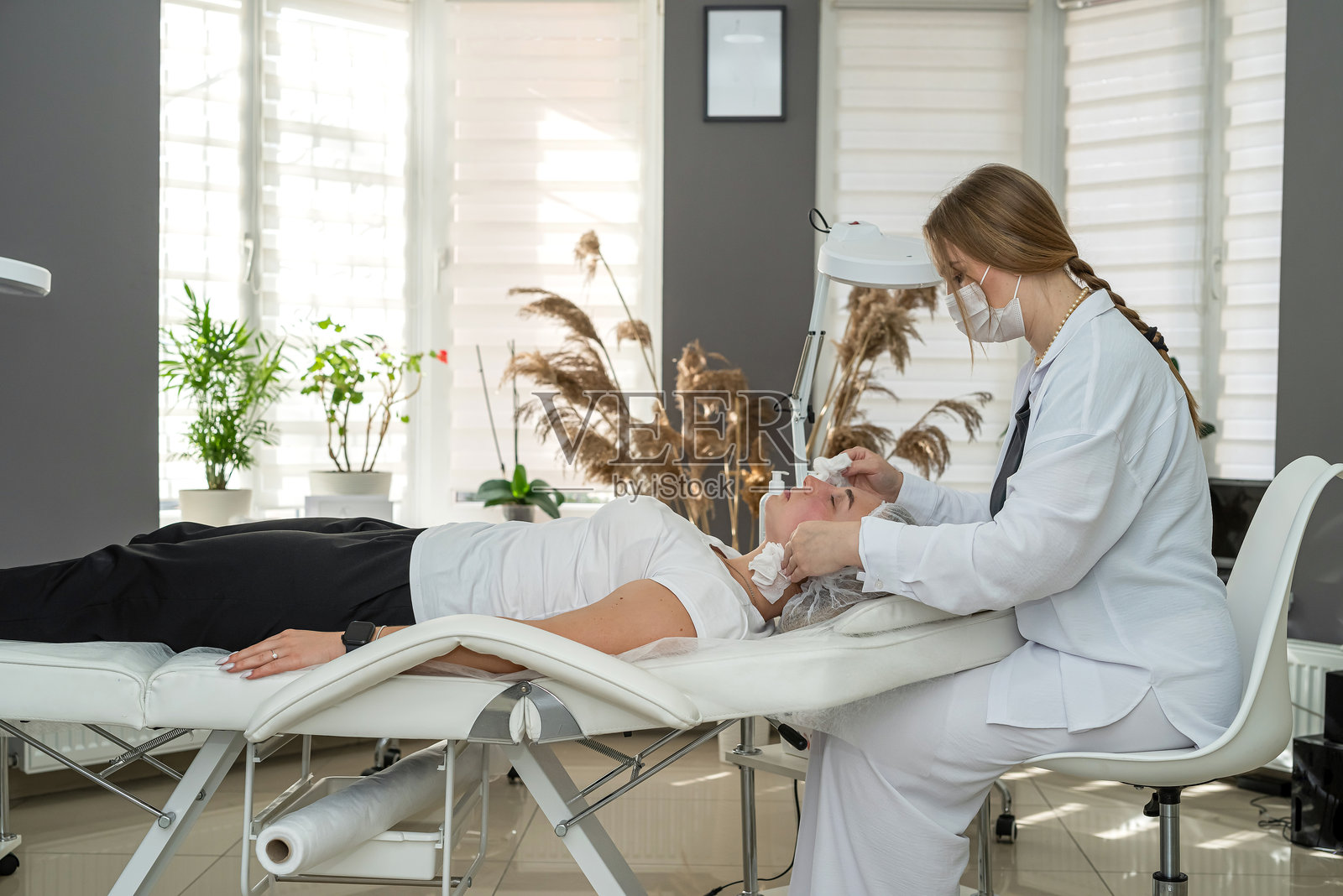 一位女士在美容院躺着，接受面部滋养保湿霜护理照片摄影图片