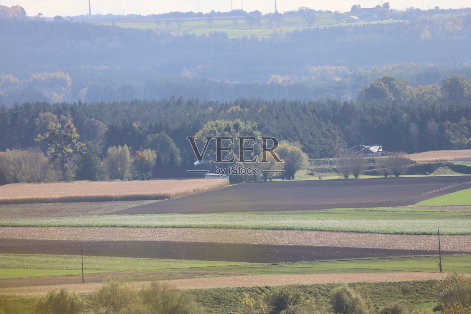 层叠的乡村田野，有森林和远处的山丘照片摄影图片