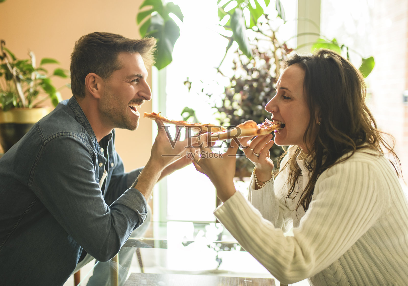 恩爱夫妻在现代厨房分享温馨时刻，共享披萨照片摄影图片