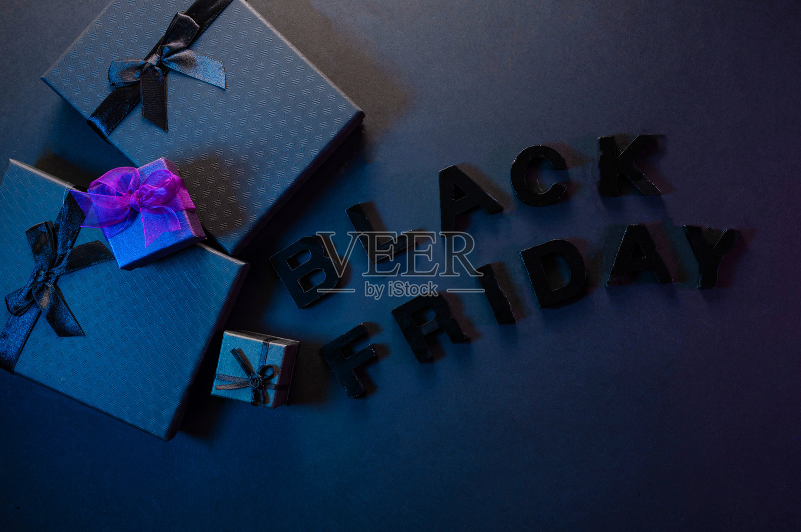 节日背景构图，以优雅的黑色礼品盒搭配黑色缎带和蝴蝶结，象征黑色星期五促销。照片摄影图片