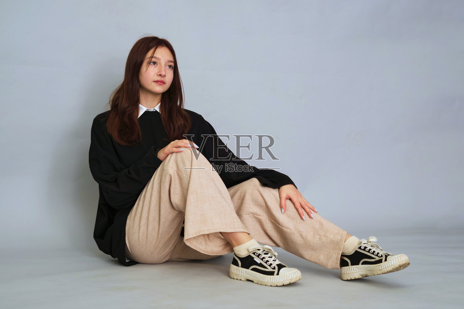 沉思的少女若有所思地坐着，她忧郁的表情反映了现代青少年成长的复杂性。照片摄影图片