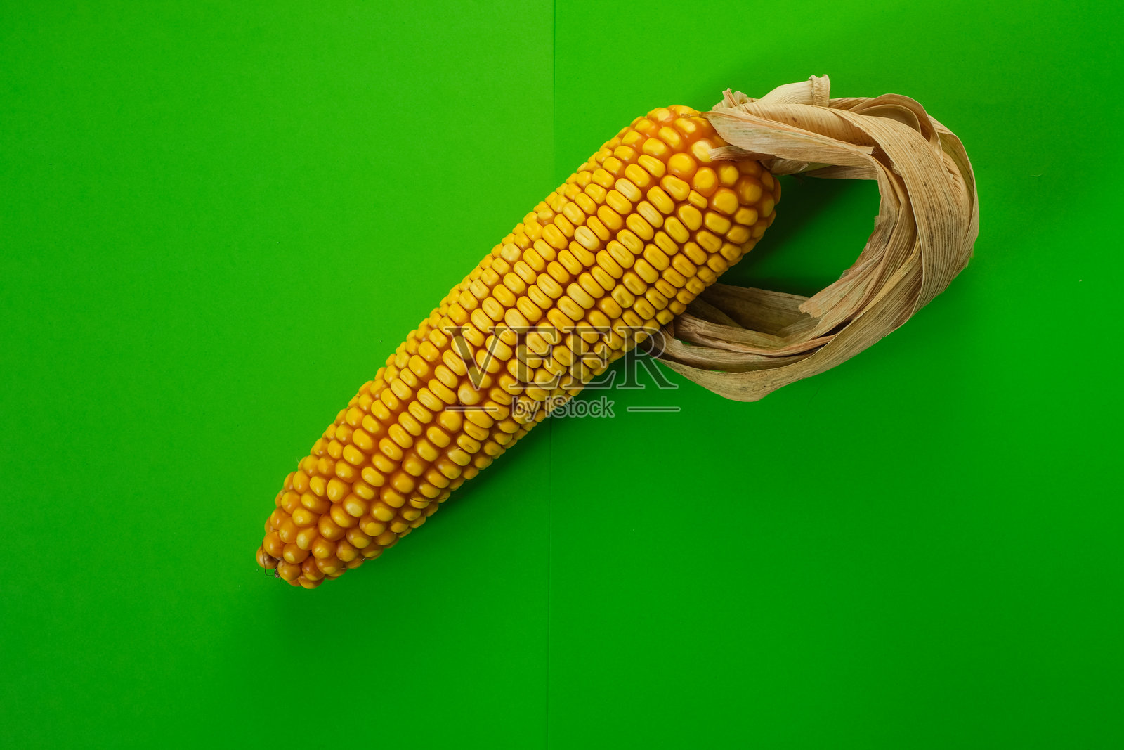 玉米芯作为乙醇汽油泵，背景为亮绿色。照片摄影图片