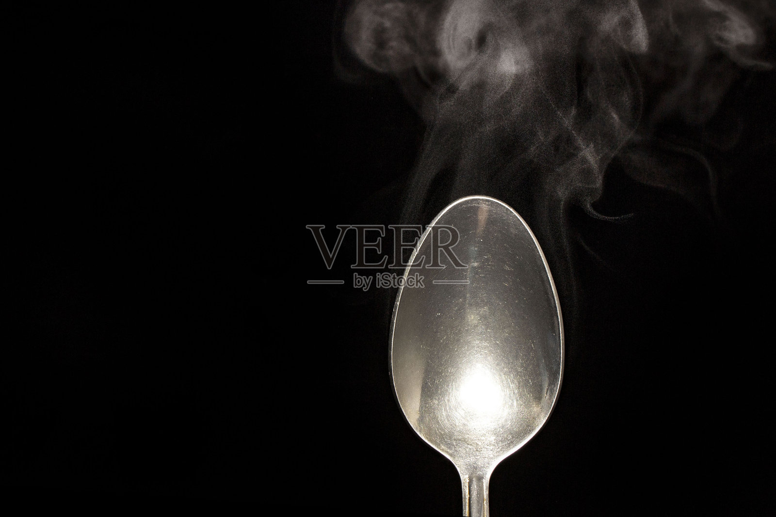 黑色背景下的热钢勺，有水蒸气升腾照片摄影图片