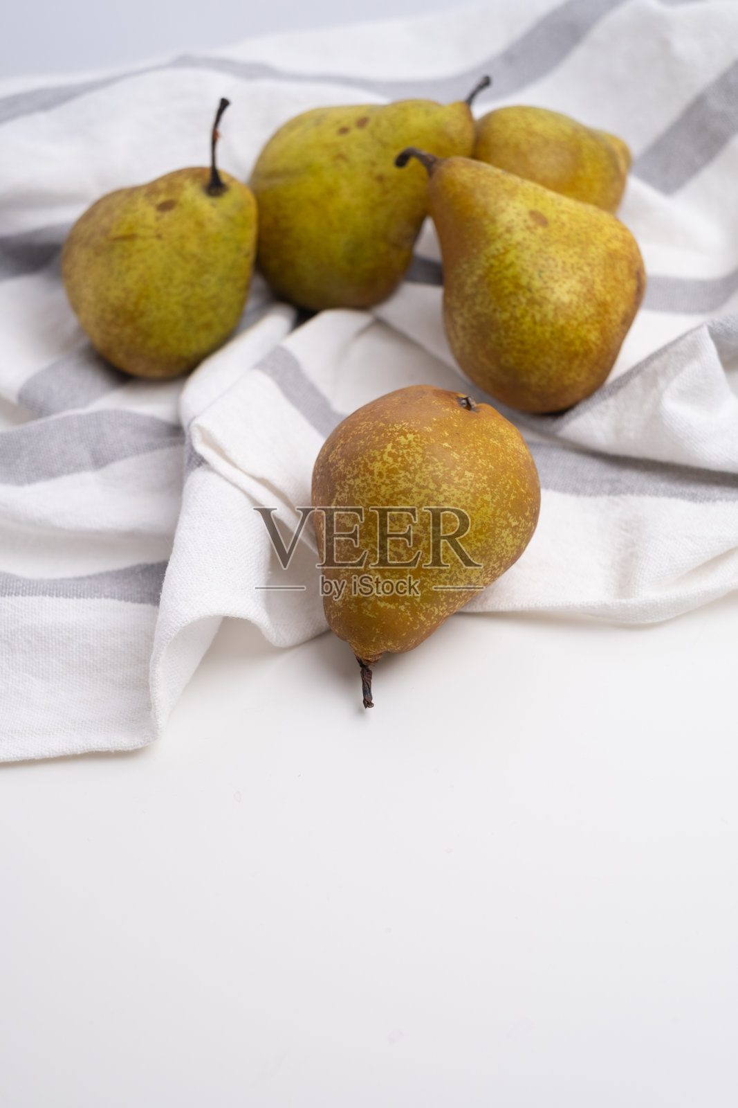 成熟新鲜的梨放在白色和灰色条纹的亚麻布上。健康饮食和丰收的简约概念。照片摄影图片