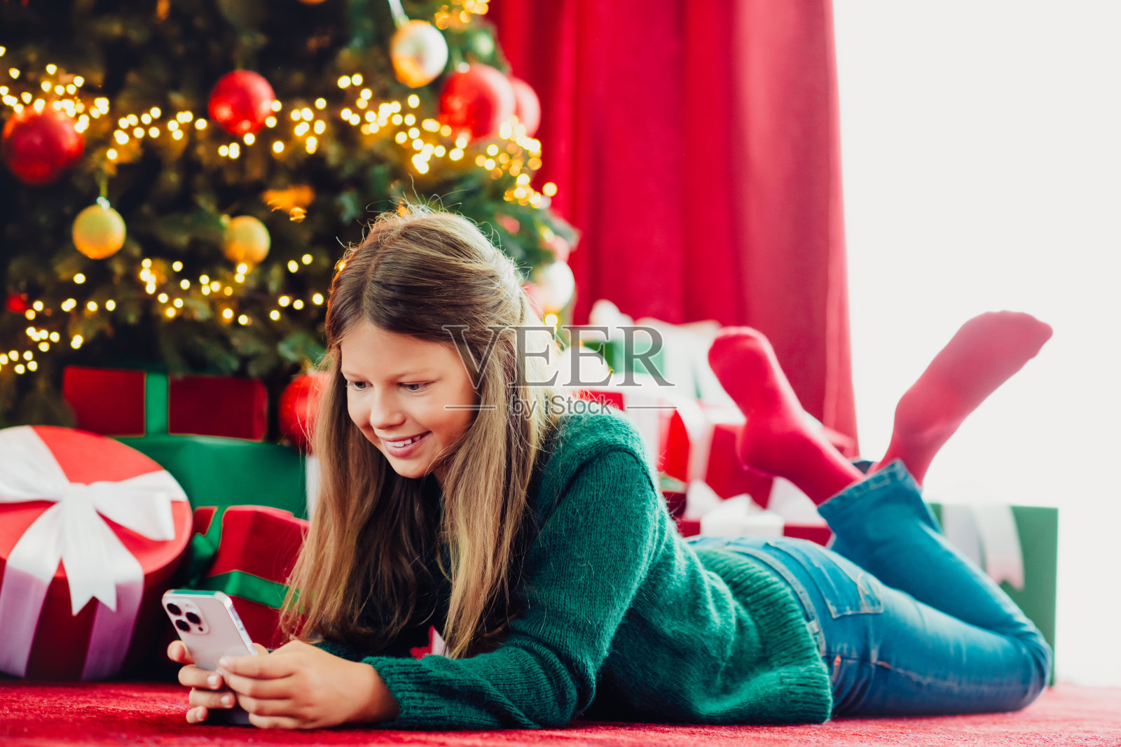女孩在家享受温馨的平安夜，有圣诞树灯光、礼物和浓浓的节日气氛，这是一个有趣的圣诞时刻。照片摄影图片
