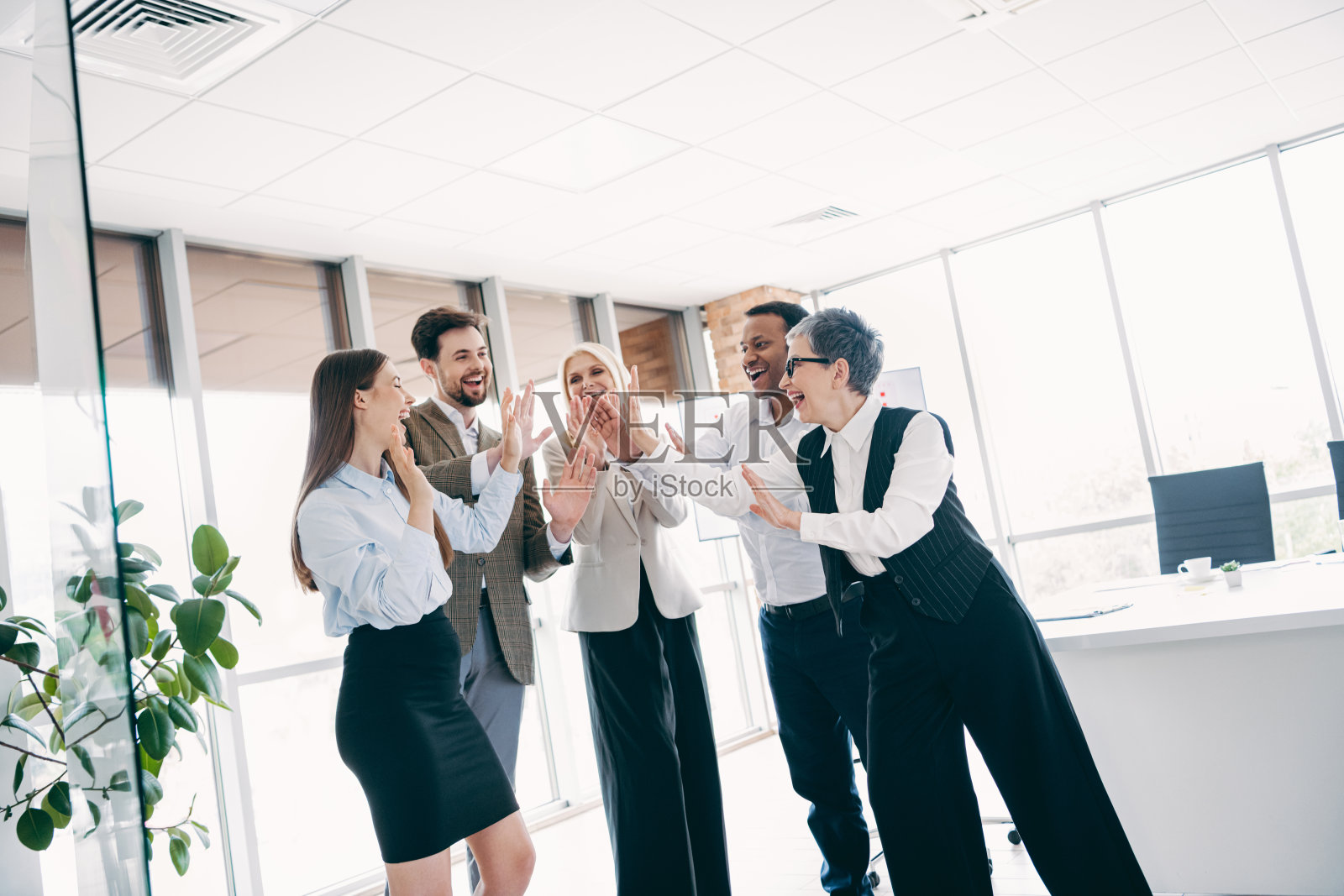 多元化的同事团队在一个现代化的办公空间里，充满活力和激励地共同庆祝照片摄影图片