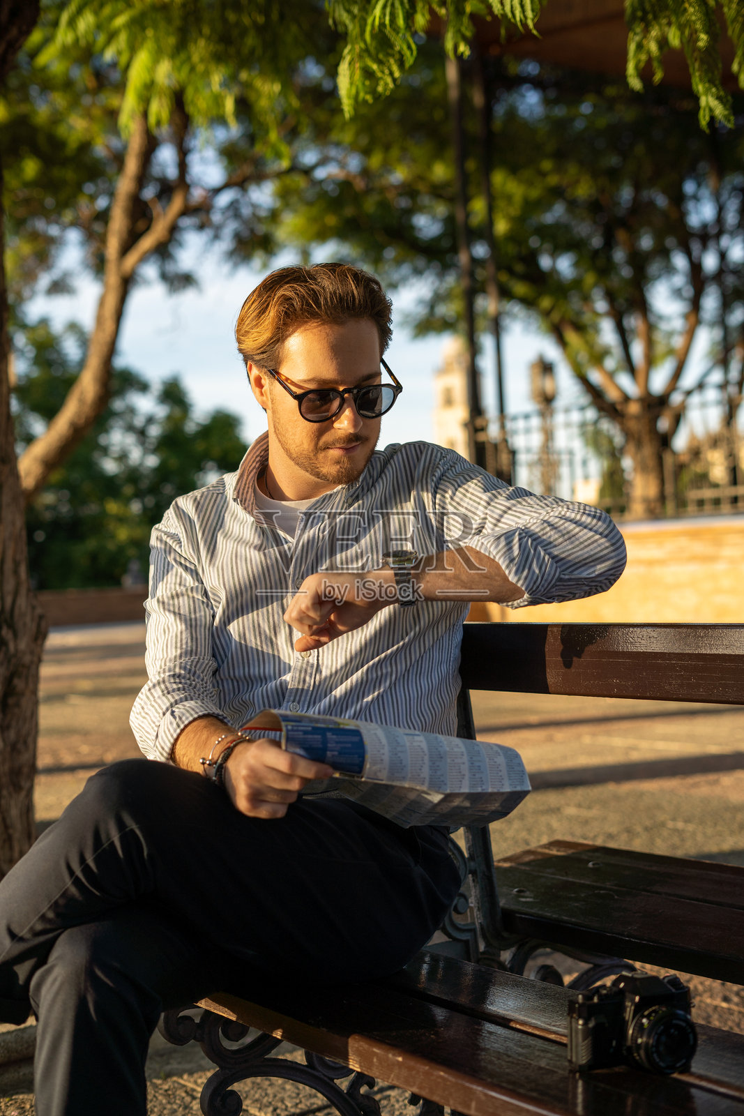 年轻男子在公园等待时看表照片摄影图片