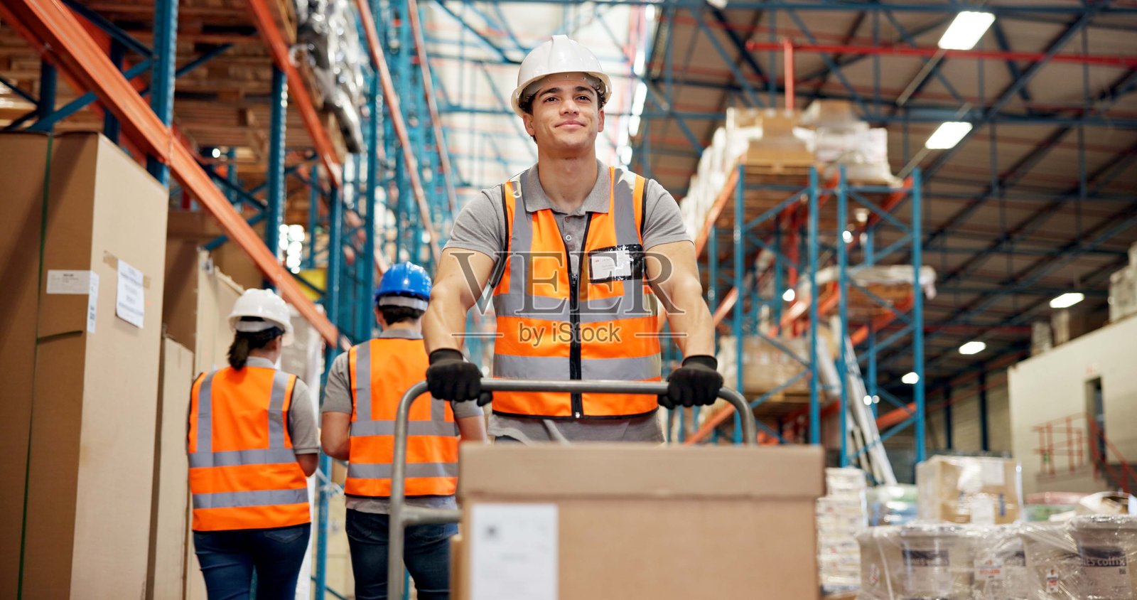 仓库中的物流手推车和男子，准备发货或库存管理，用于配送。仓库中的配送、个人防护装备和装卸工，用于直运或供应链中的出口管制。照片摄影图片