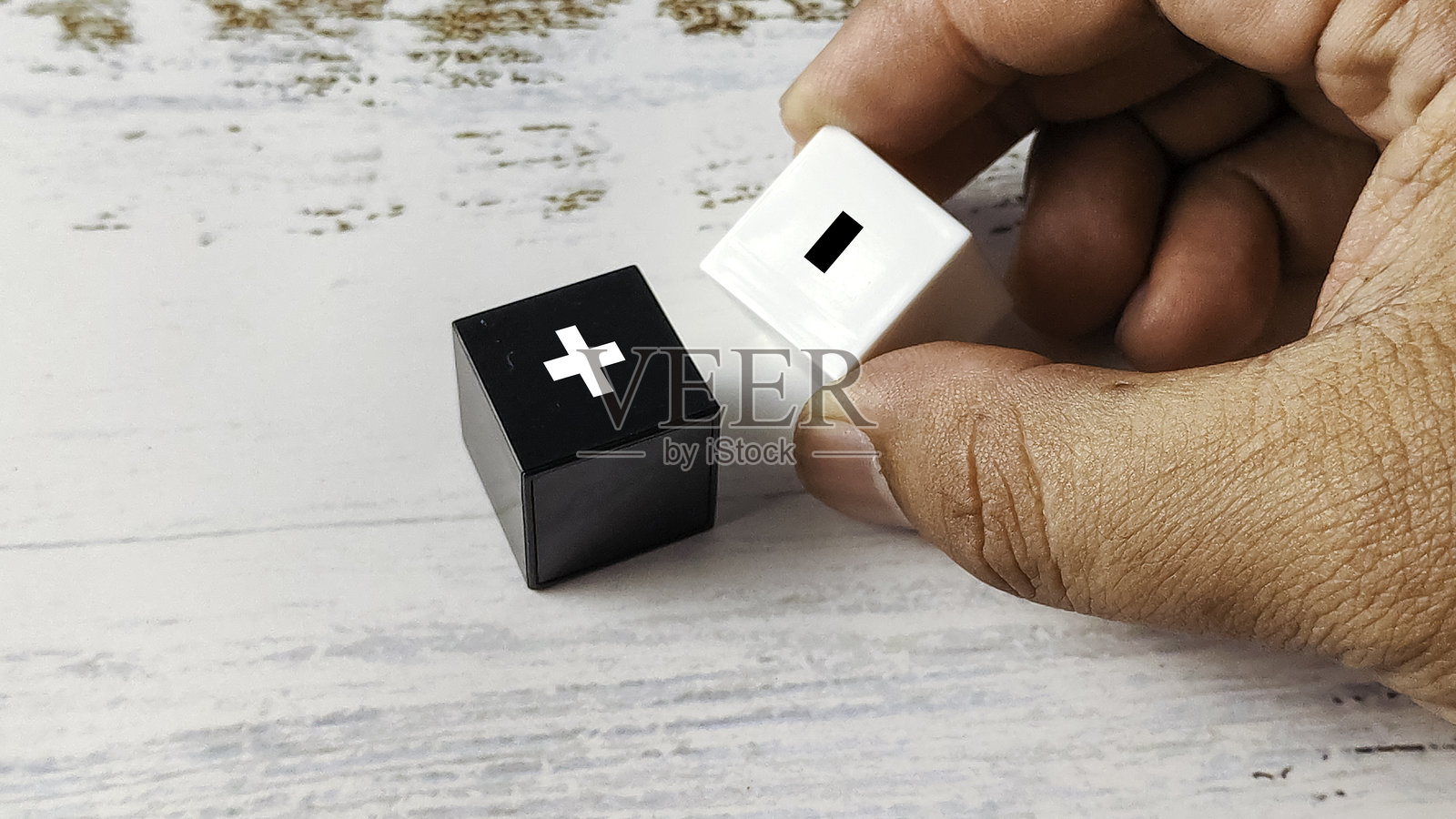 手持黑白方块，上面带有加号和减号符号，代表比较、优缺点和决策照片摄影图片