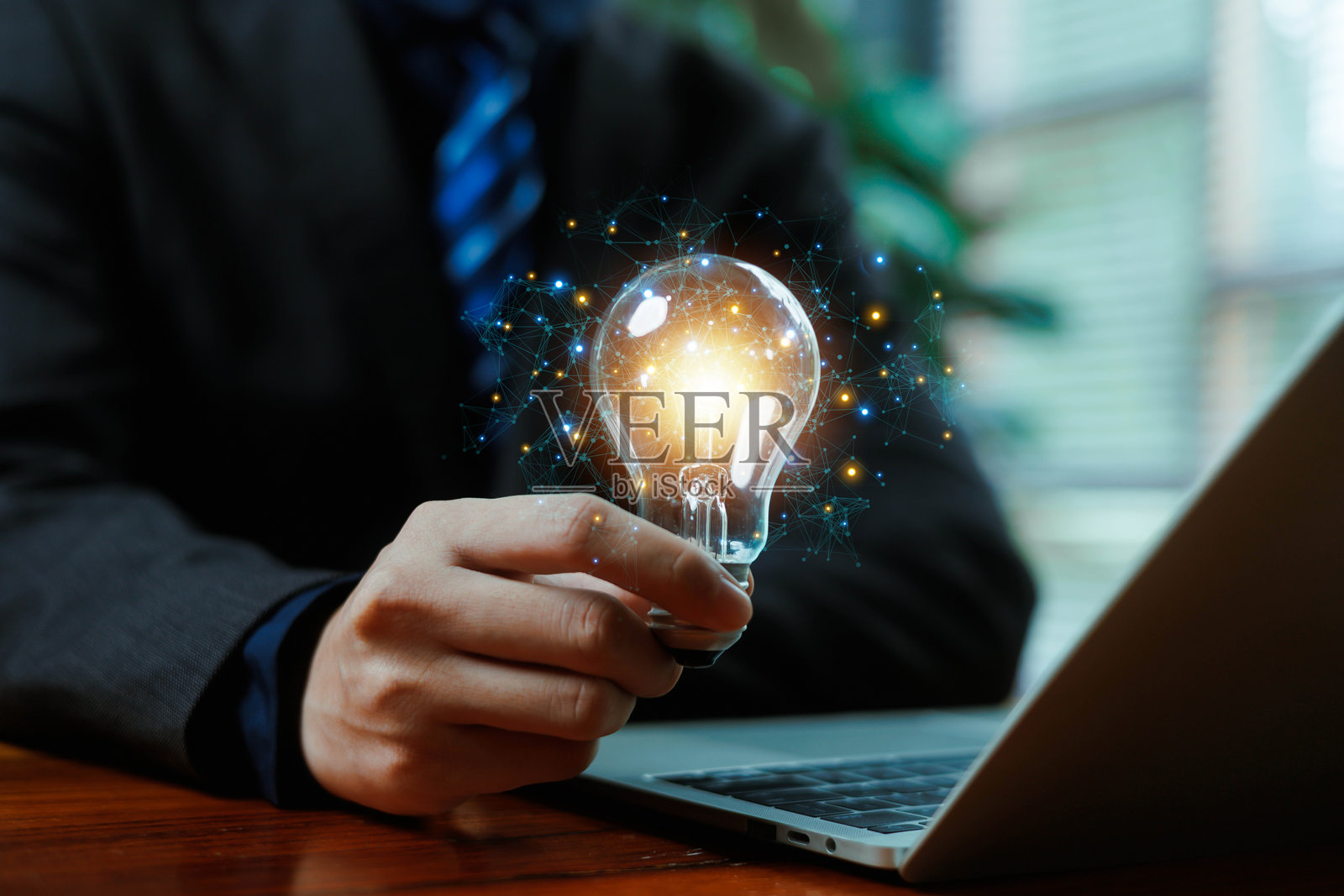 一位商人举着发光的灯泡，上面连接着数字网络，象征着创新、创意、智能想法、技术解决方案和现代商业发展。照片摄影图片