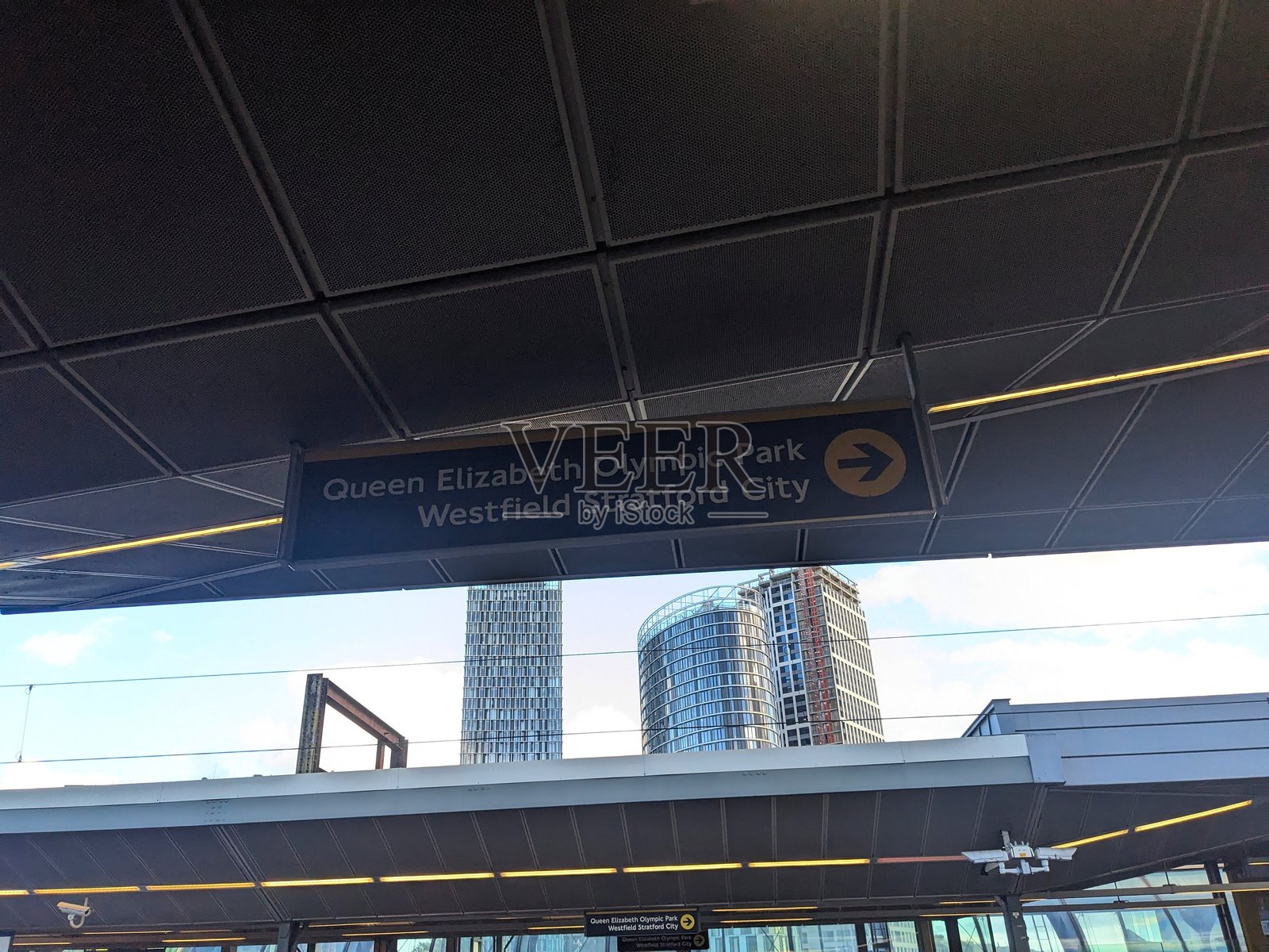 从低角度看到的斯特拉特福德车站标志，指向奥林匹克公园和韦斯特菲尔德，背景是斯特拉特福德的天际线照片摄影图片