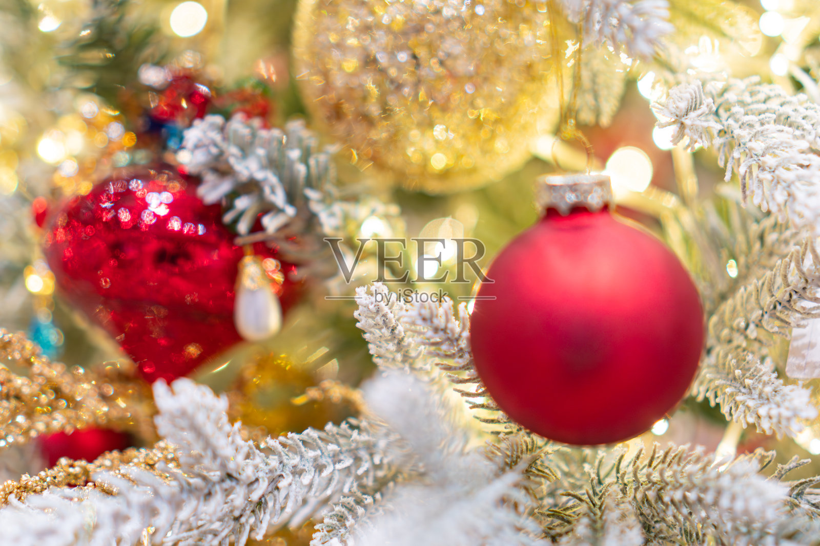 在温暖灯光下，房间背景模糊，一棵装饰着鲜艳红金色饰品的圣诞树被放置在显眼位置。照片摄影图片