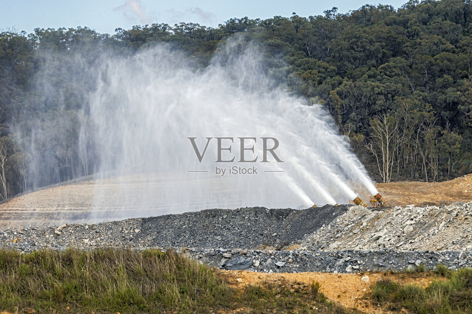喷水装置正在给露天（地表）矿山复垦区进行喷水湿润。照片摄影图片