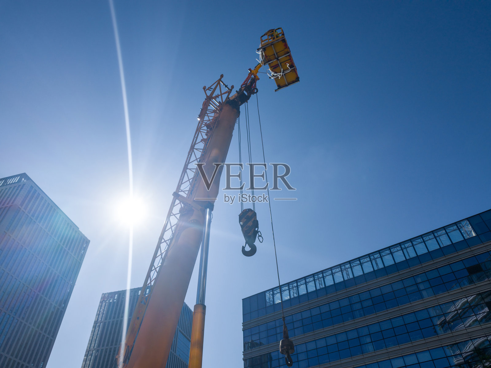 在晴朗的蓝天下，阳光明媚，起重机在城市建筑工地上作业照片摄影图片