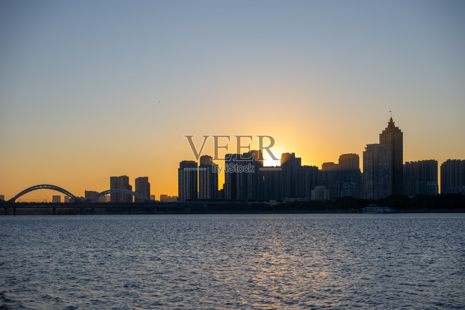 现代建筑和跨水大桥映衬下的城市天际线壮丽日落景观照片摄影图片