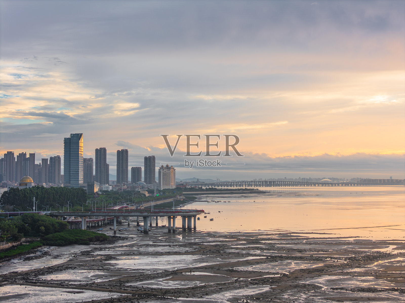 现代摩天大楼和横跨水面的桥梁，城市海岸线美丽的日落景观照片摄影图片