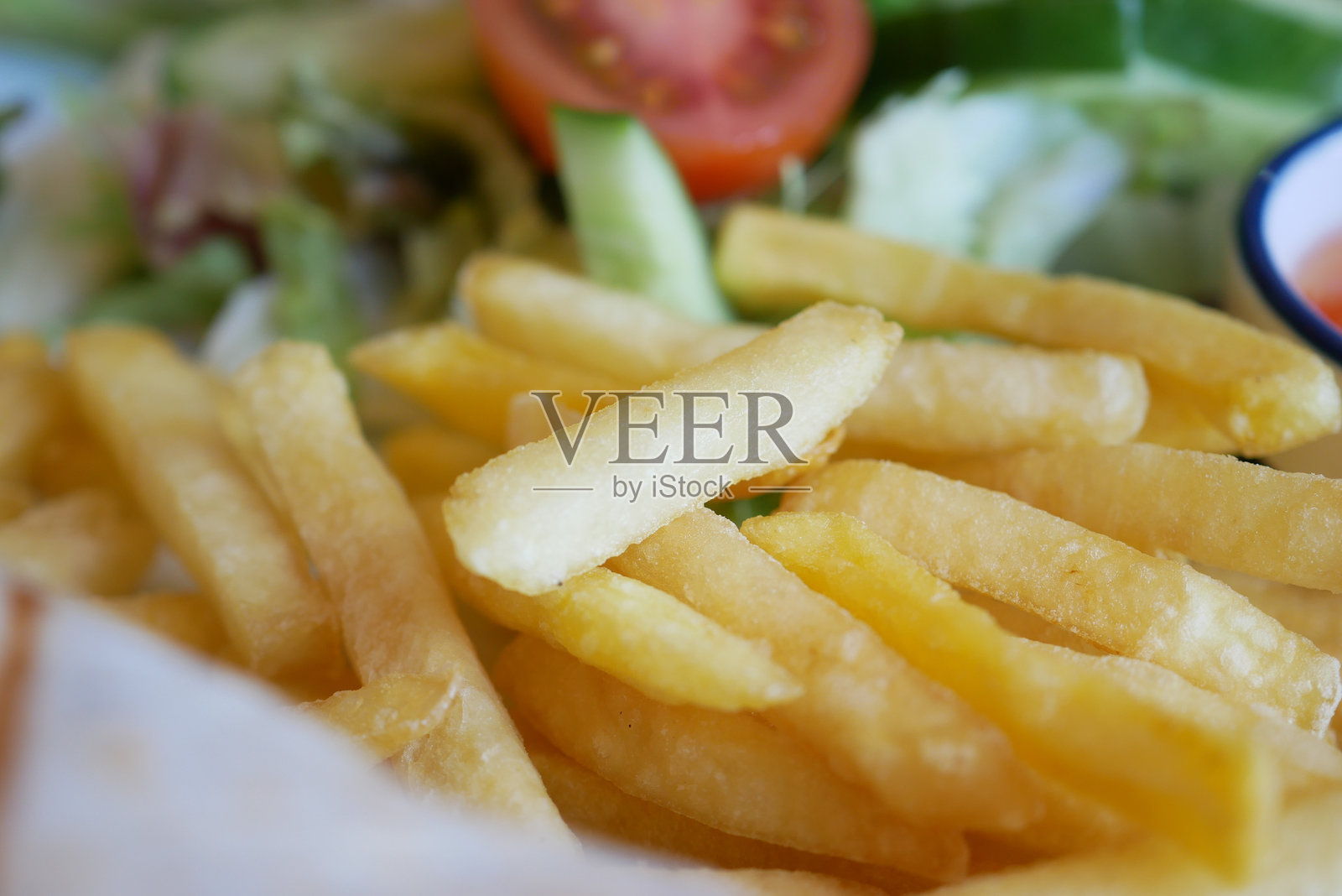酥脆金黄的炸薯条，搭配新鲜的沙拉和蔬菜照片摄影图片