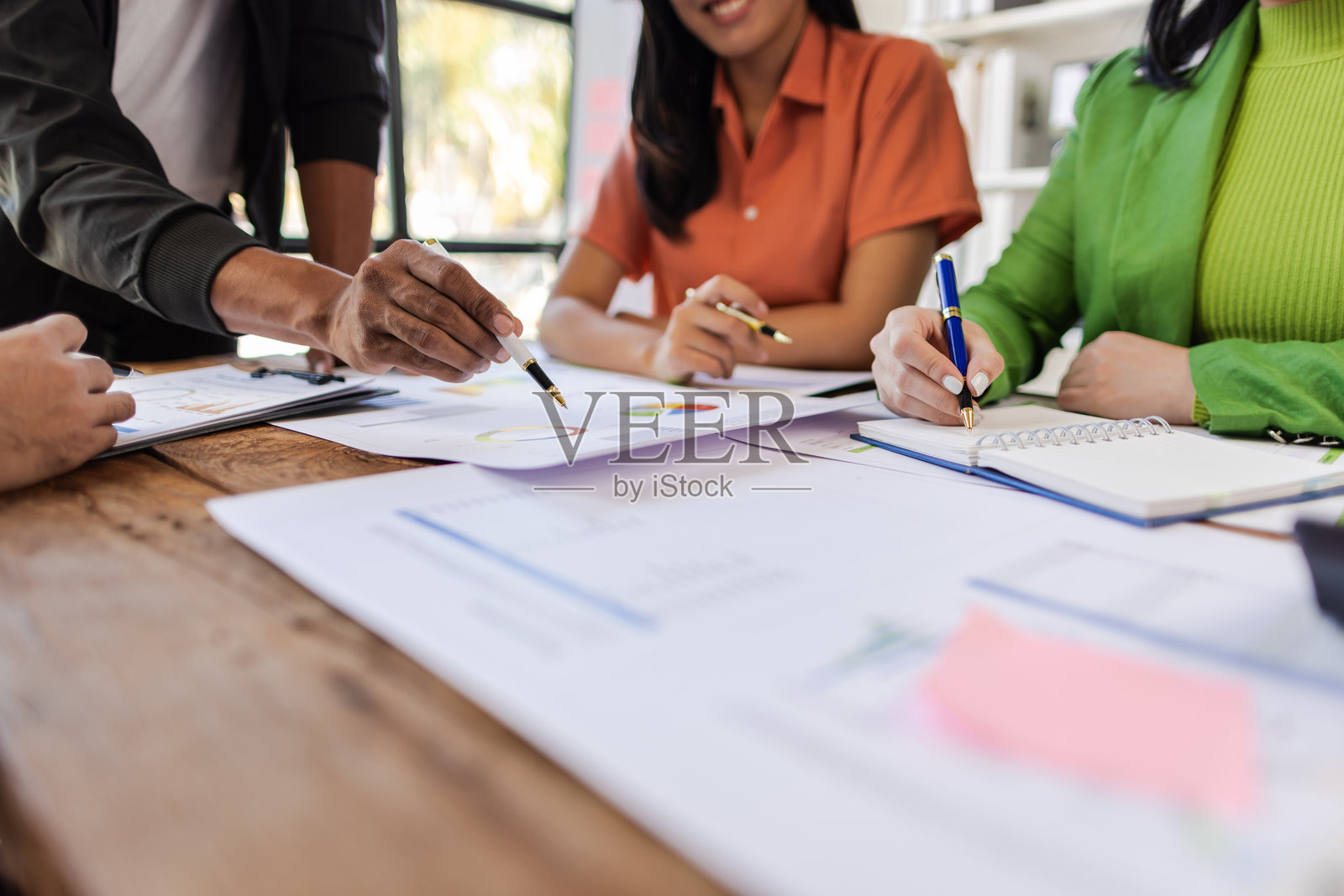 商务人士在办公室办公桌旁开会，分析财务文件并讨论创业项目。照片摄影图片