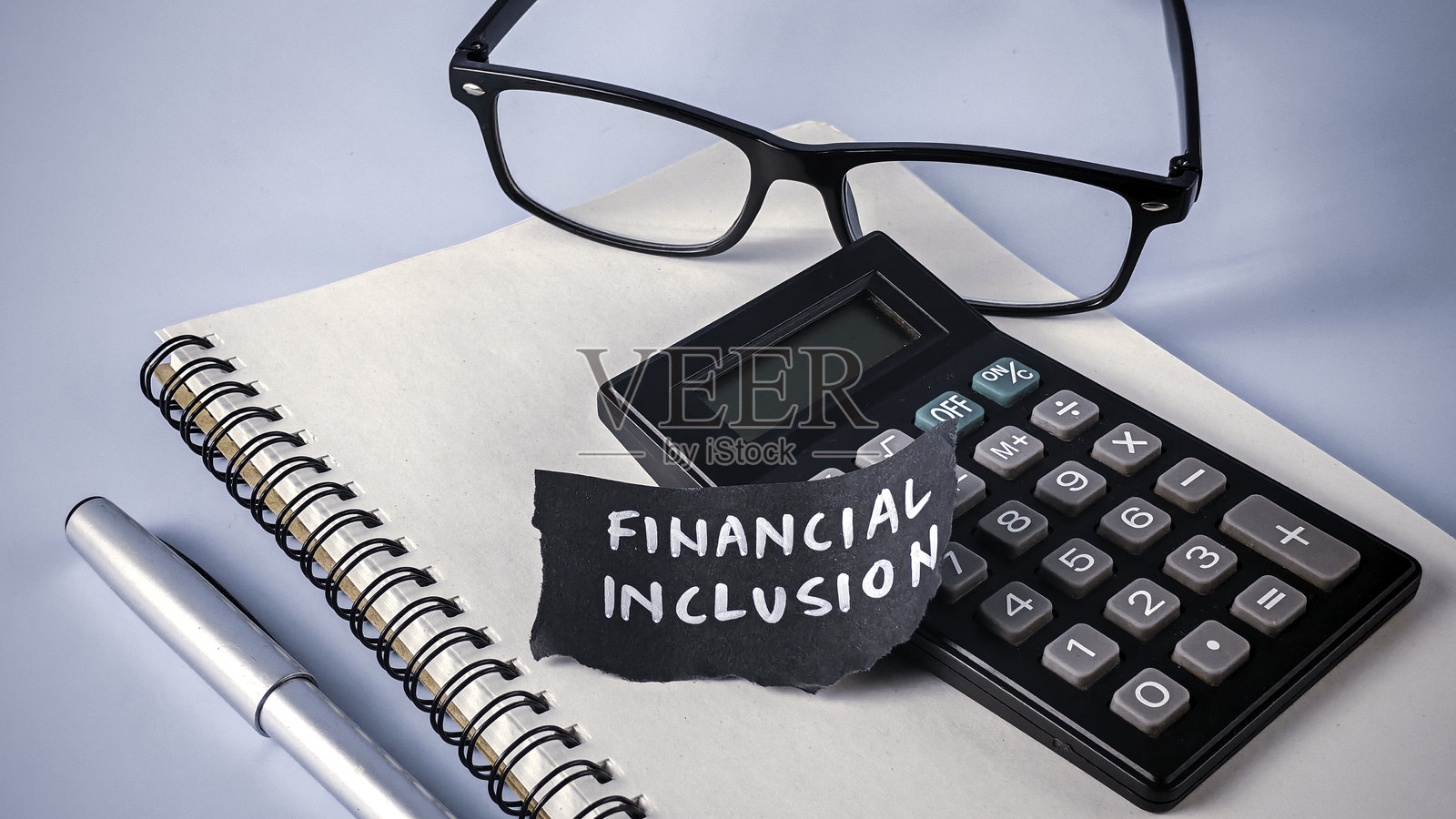普惠金融概念：计算器、眼镜和代表银行服务与经济机会均等的可读文本照片摄影图片