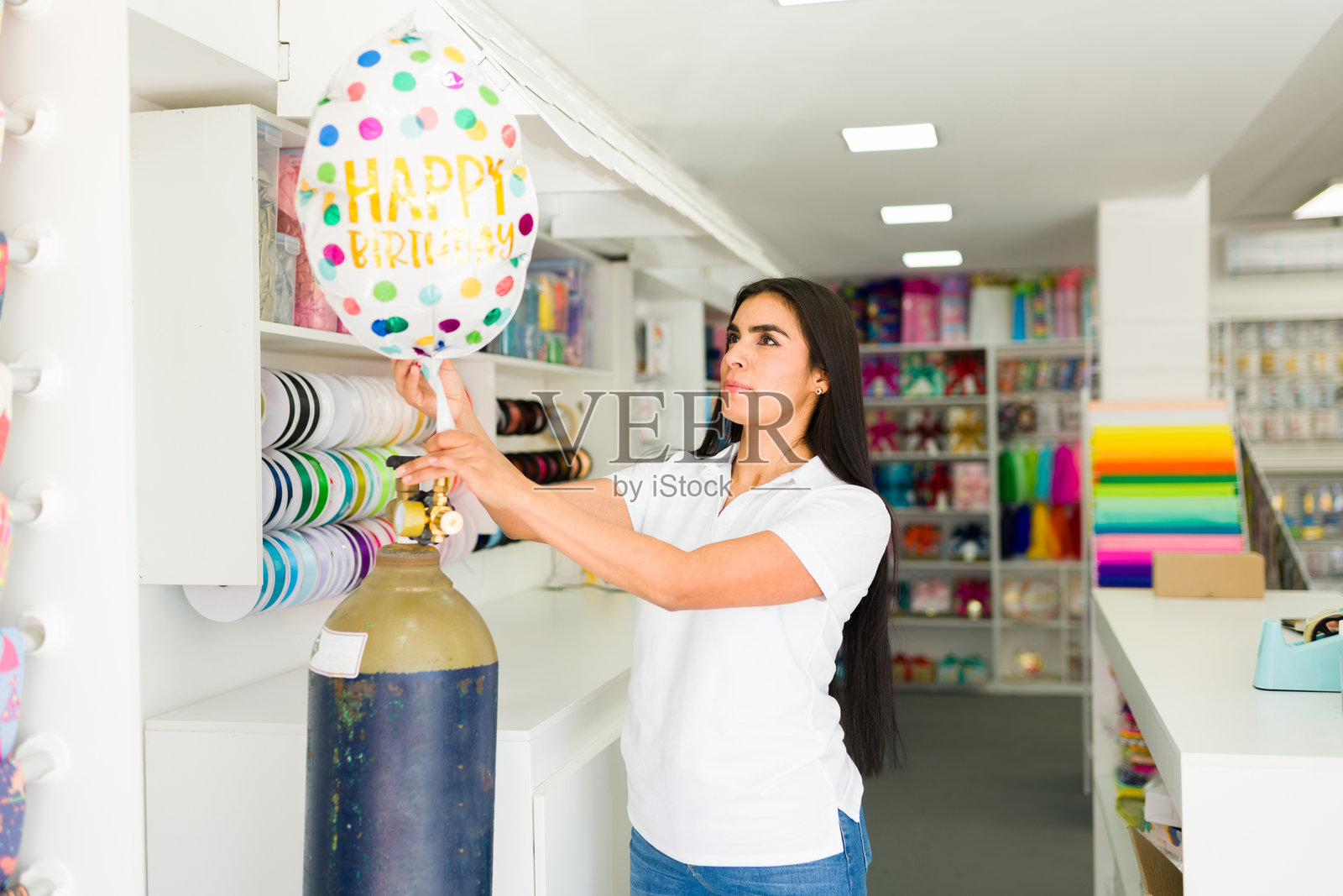 拉丁裔员工在派对用品店里给生日快乐气球打气照片摄影图片