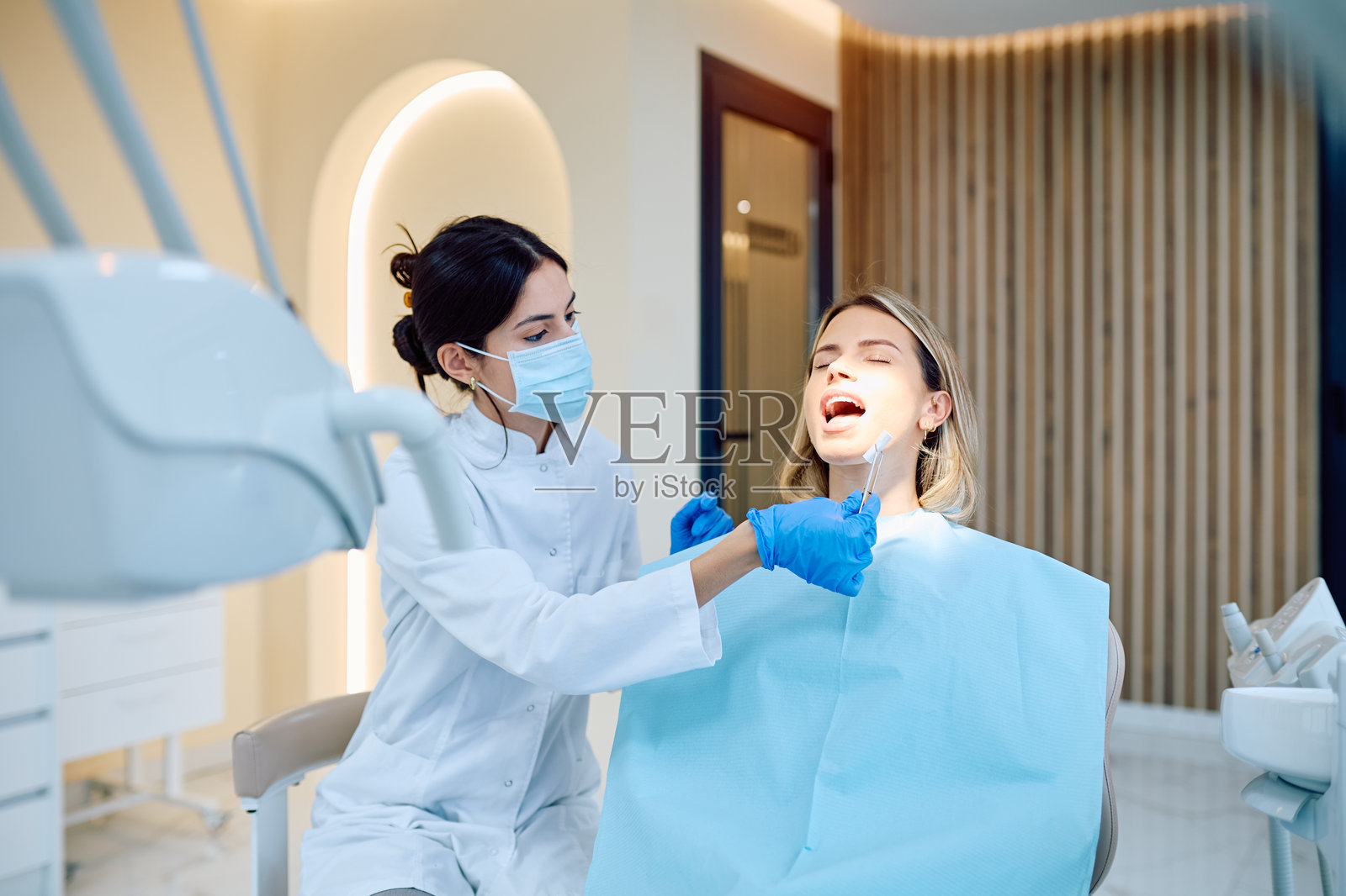 牙医在牙科检查期间检查患者的牙齿照片摄影图片