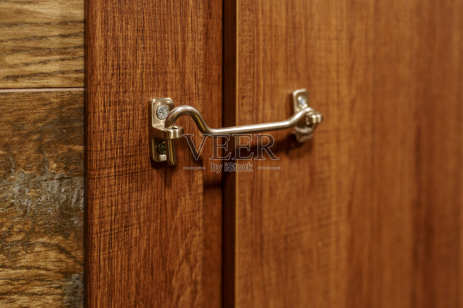 金属门闩锁在木质橱柜上，储物柜硬件，安全闭合，温暖的木纹照片摄影图片