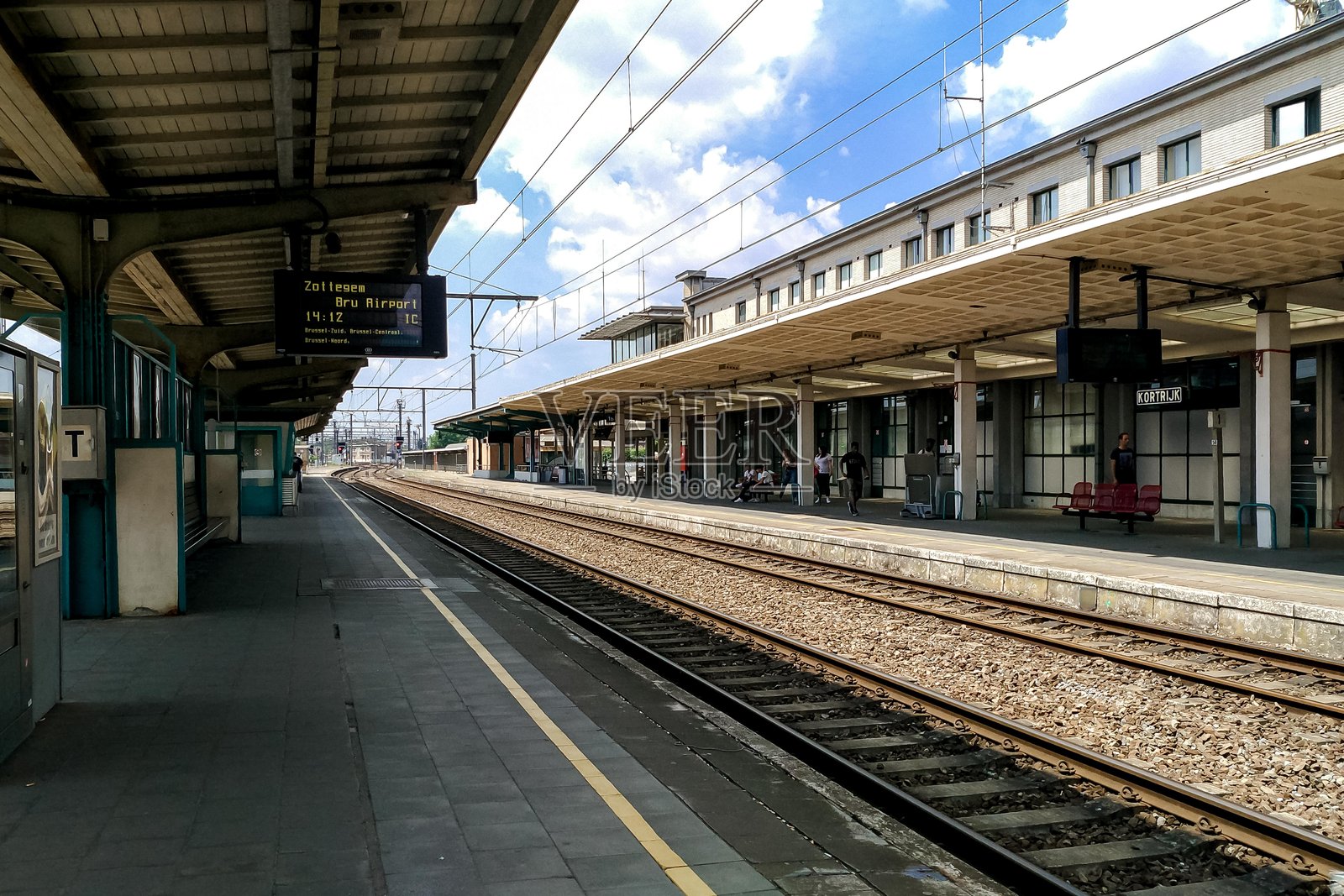 蓝天下的空旷火车站台，有铁轨和建筑照片摄影图片