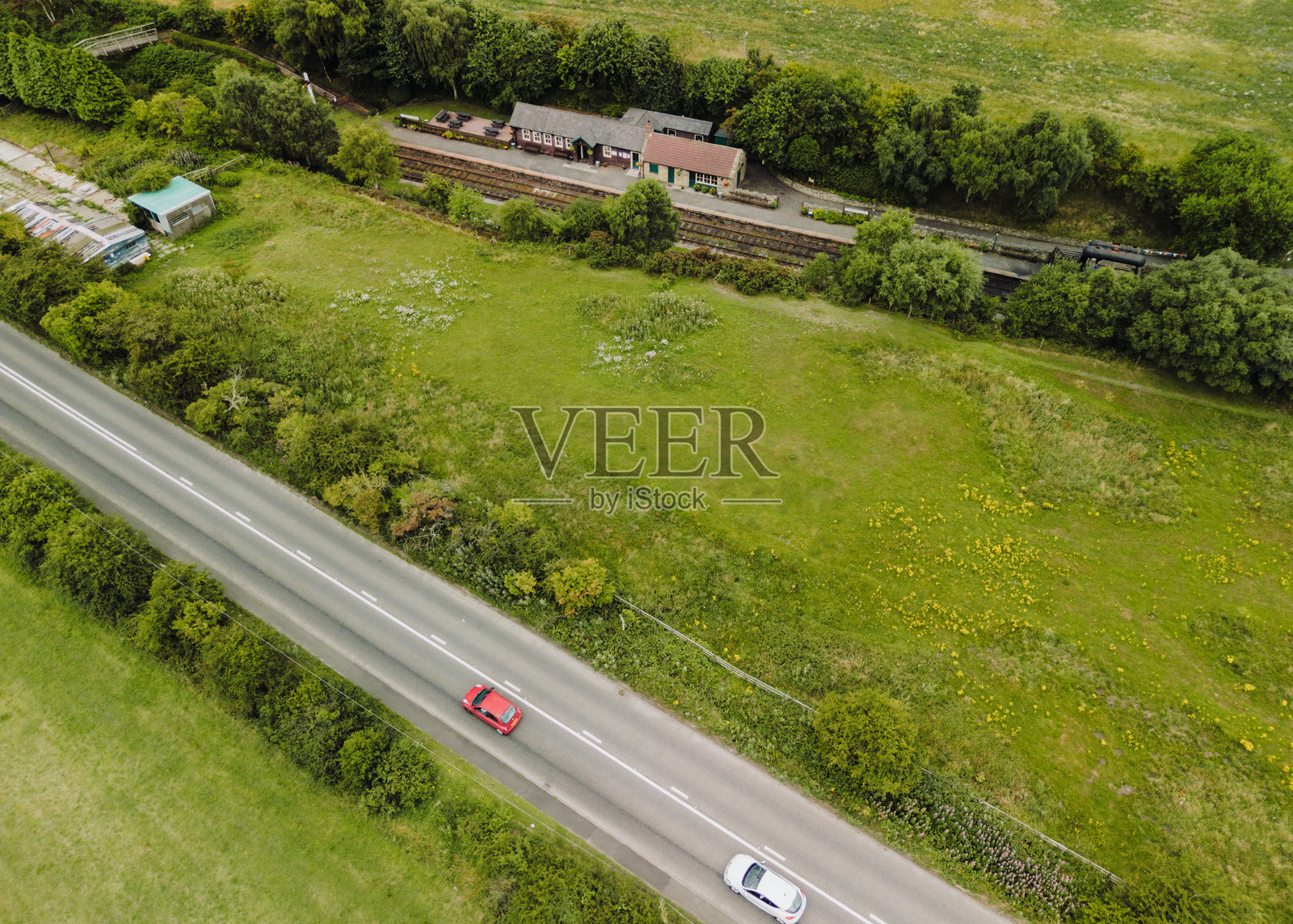 无人机视角下的达勒姆郡的坦菲尔德铁路，展示了安德鲁斯站及其旁边被葱郁绿植环绕的公路照片摄影图片