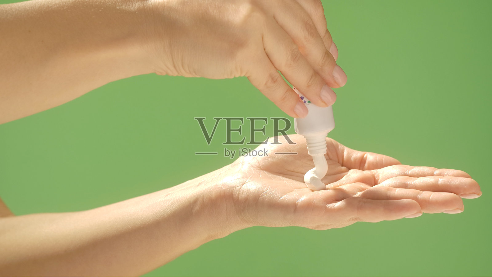 绿色背景下涂抹乳霜的手照片摄影图片