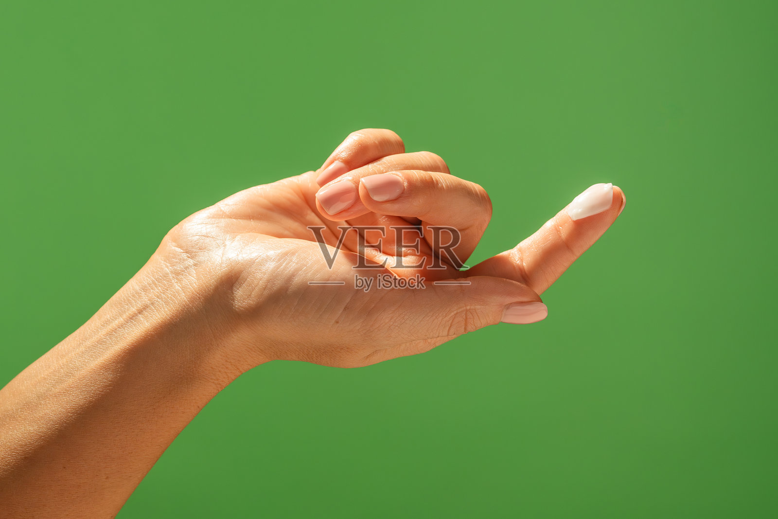 绿色背景下指尖涂抹着乳霜的手部特写照片摄影图片