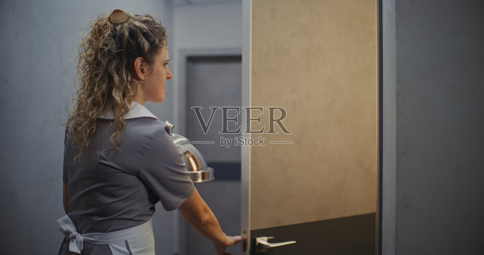 友好的女酒店服务员，身穿灰色制服，送餐上门照片摄影图片