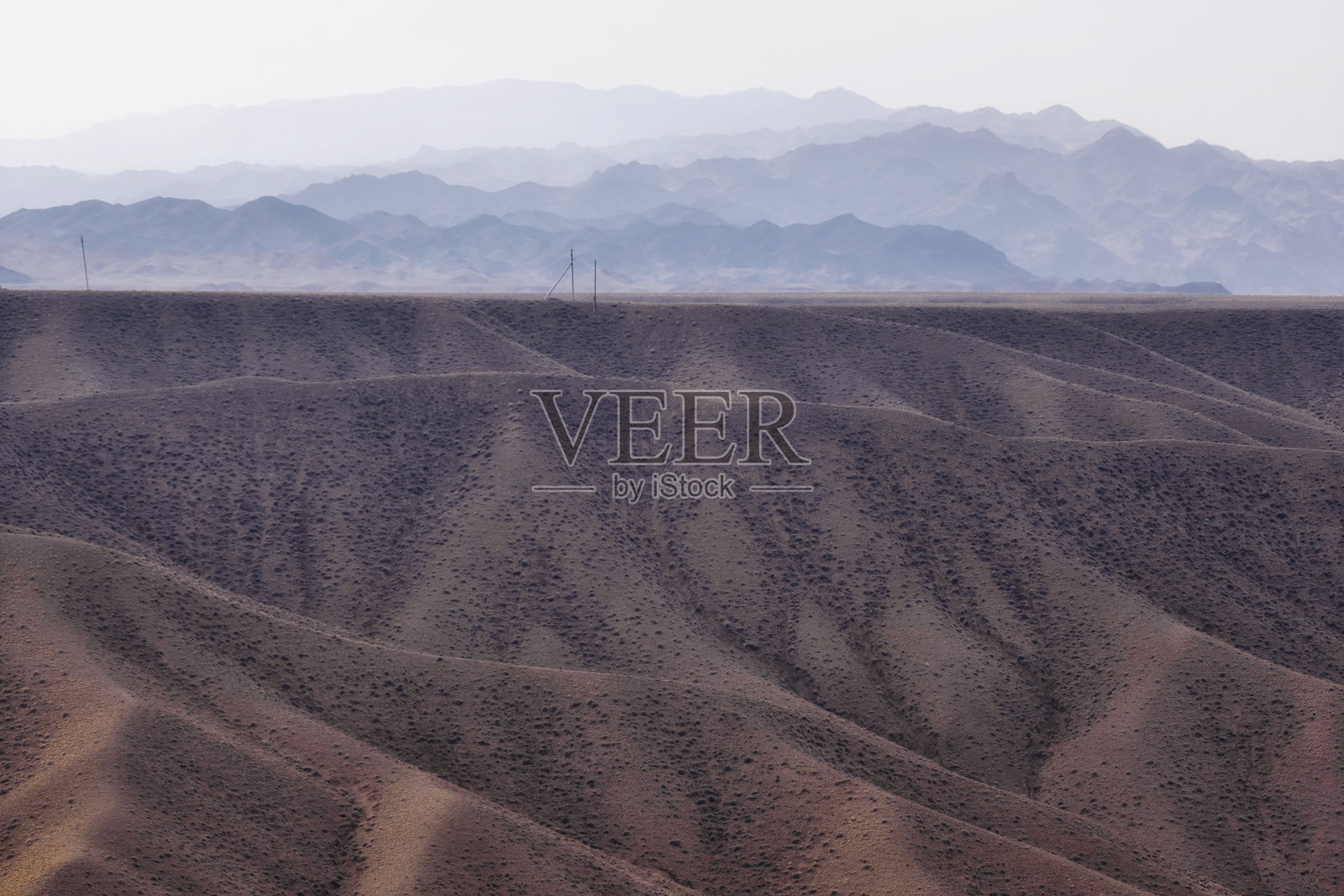 哈萨克斯坦阿拉木图地区，贴里力克峡谷（Timerlik Canyon）的山坡层叠起伏，以深沉的秋季色调描绘，背景是地平线上若隐若现的山脉。照片摄影图片