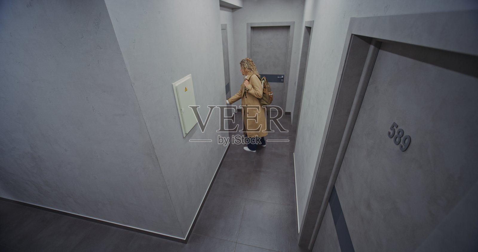 穿着浅色风衣的时尚女旅行者走在酒店走廊上照片摄影图片