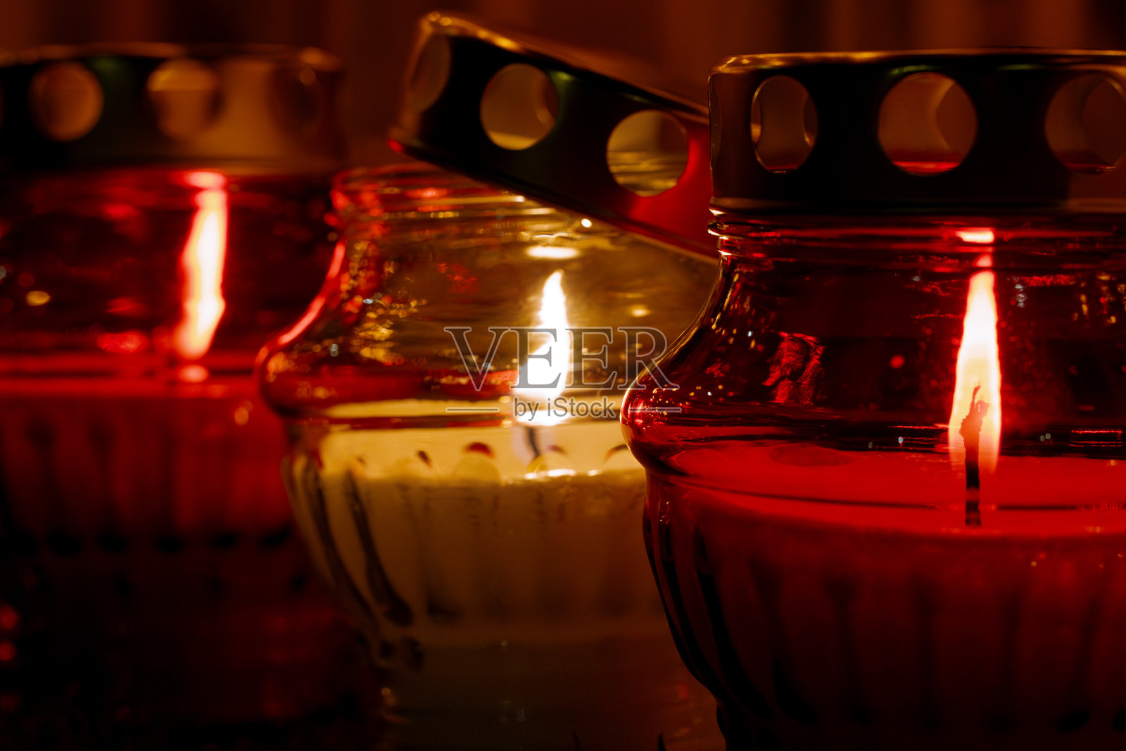 红色玻璃灯笼中燃烧的纪念蜡烛特写，温暖的光芒象征着缅怀、信仰和希望照片摄影图片