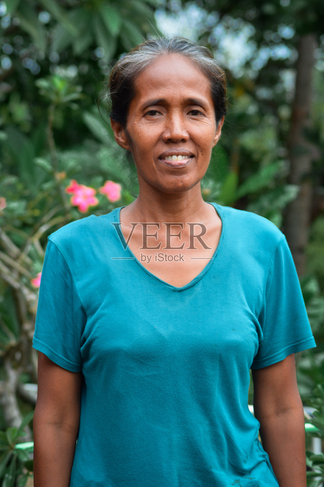 近景肖像：一位穿着蓝色衬衫、面带微笑的老年农妇照片摄影图片