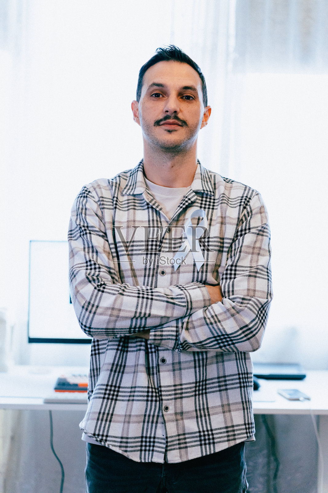 一位自信的男士肖像，胸前佩戴蓝色丝带，支持‘Movember’活动和男性健康意识照片摄影图片