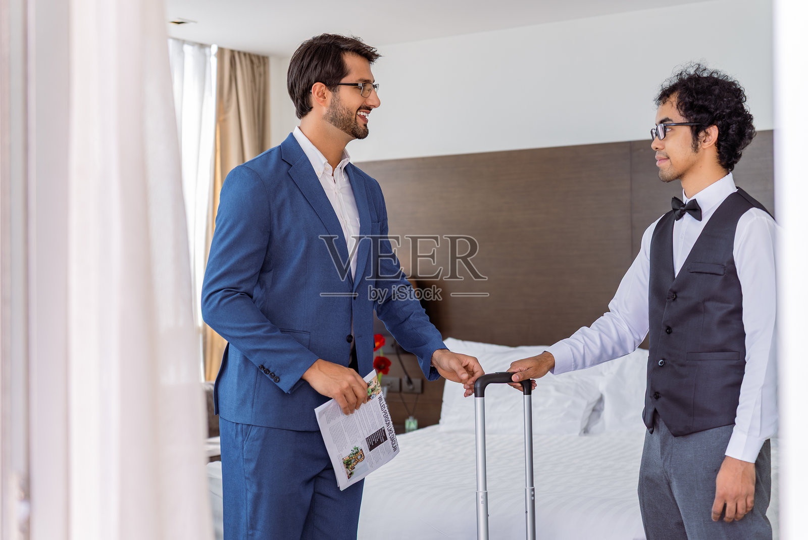 一位拉丁商人在豪华酒店房间里热情地迎接一位中东行李员照片摄影图片