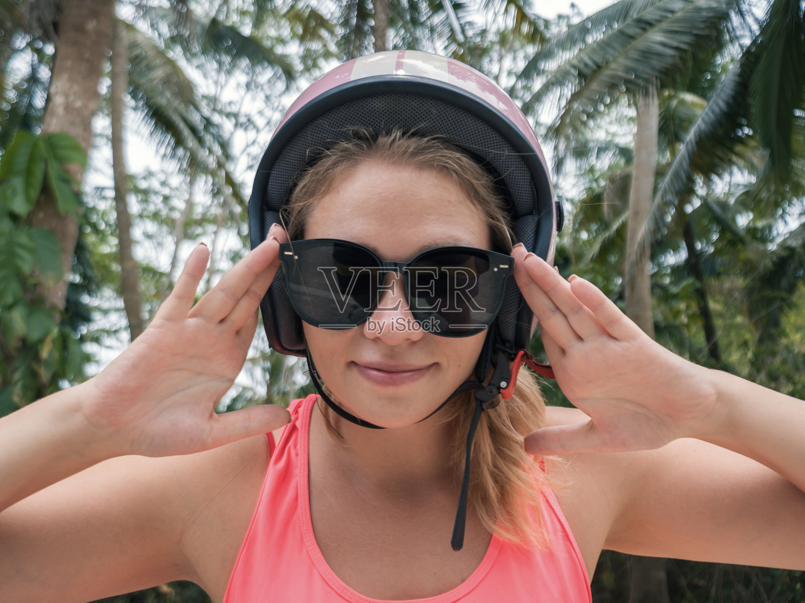 戴着头盔和太阳镜的女冒险家，在葱郁的环境中准备进行热带户外活动。照片摄影图片