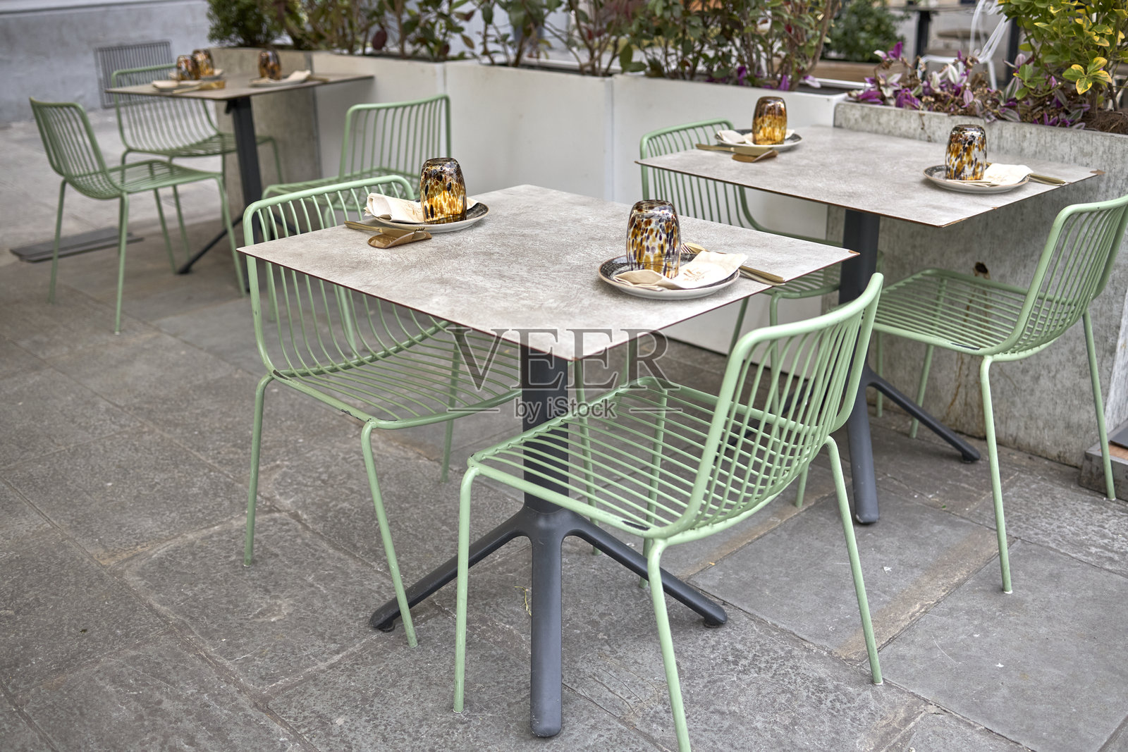 石砌露台上黄色遮阳伞下的户外咖啡馆桌椅照片摄影图片