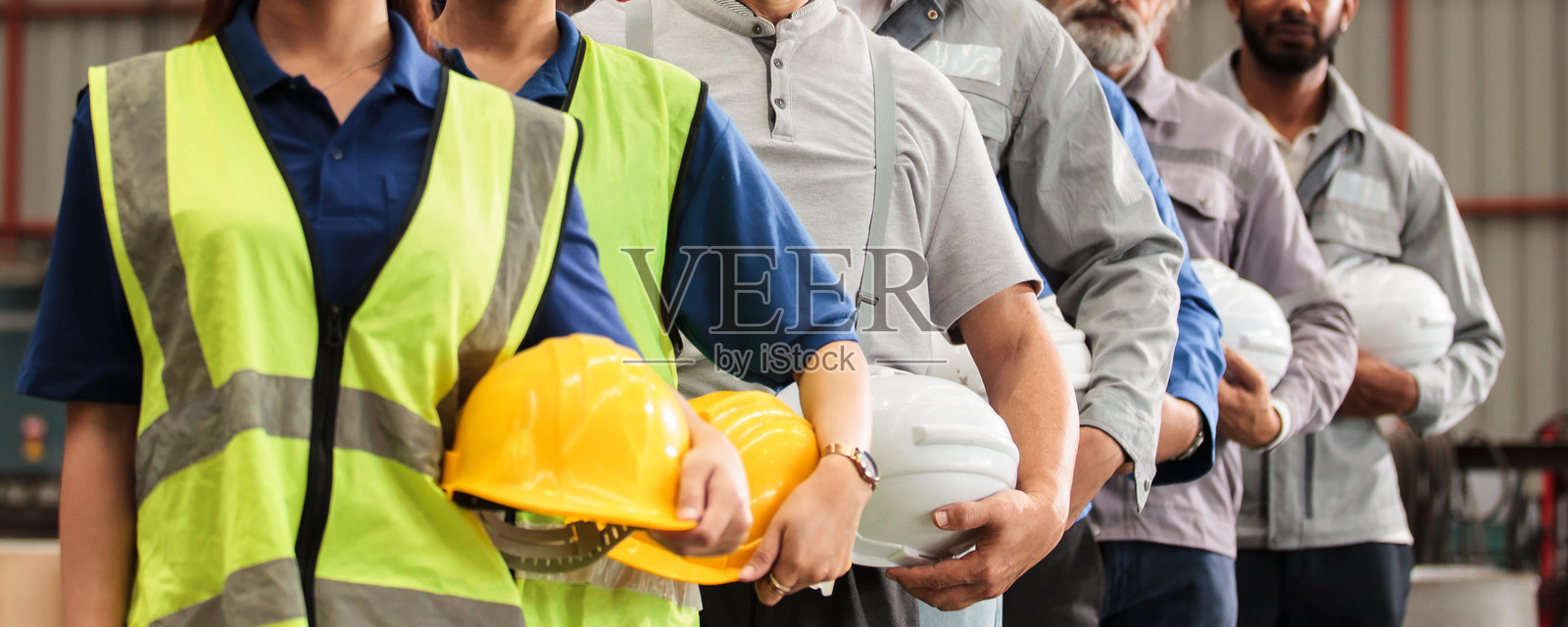 工程师和工厂工人在排队，都戴着安全帽照片摄影图片
