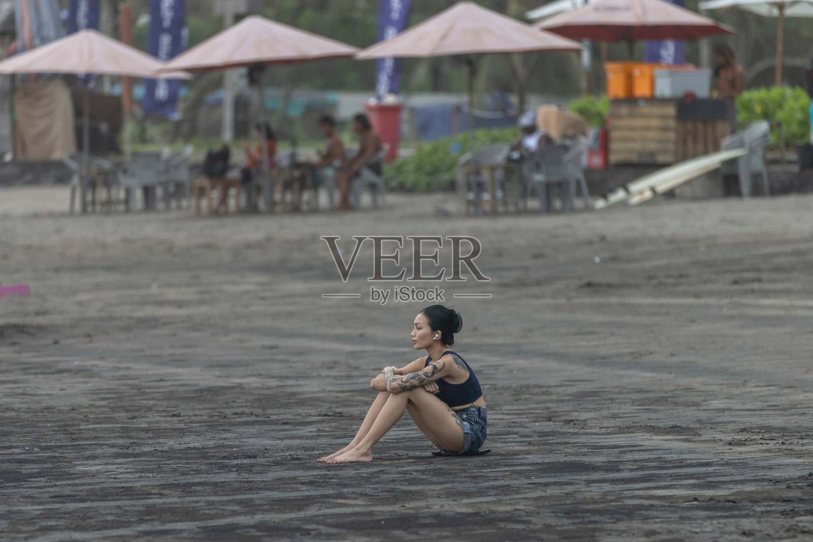 年轻的亚洲女性在日落时分坐在沙滩上眺望海景。照片摄影图片