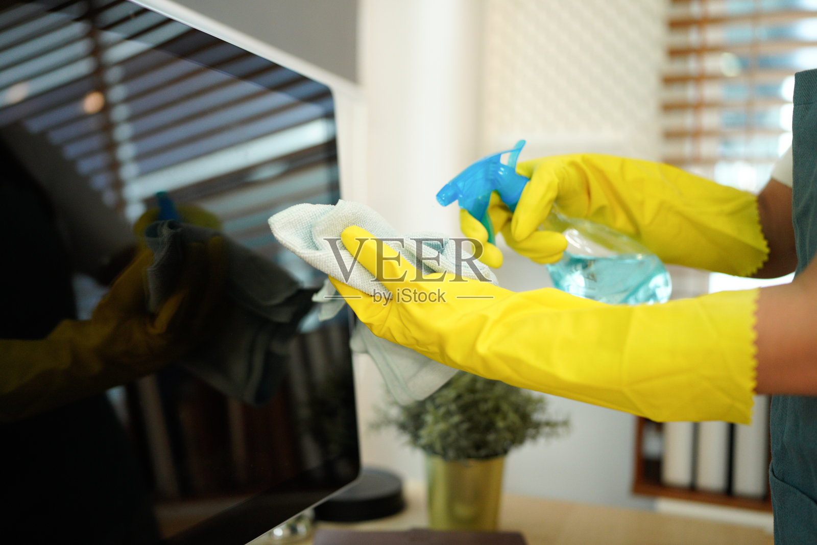 清洁服务处的女工在办公室擦拭电脑屏幕照片摄影图片