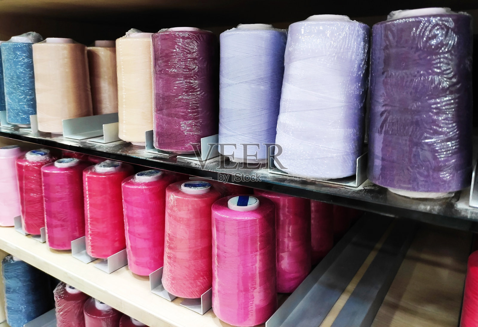工艺品店展示柜中一排排琳琅满目的彩色线轴，缝纫线有各种颜色和不同的色调照片摄影图片