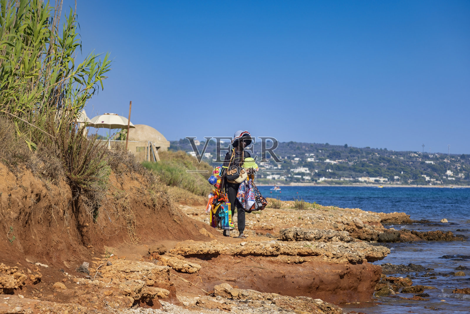 非洲海滩上的商贩在意大利海滨度假胜地马里纳迪托雷瓦多沿着海滩售卖商品照片摄影图片