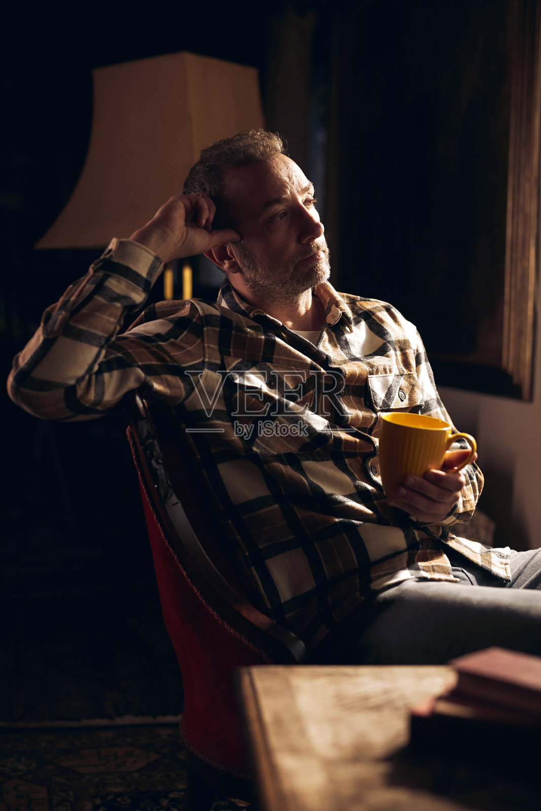 秋冬季节，一个人在家里拿着一个黄色的杯子。照片摄影图片