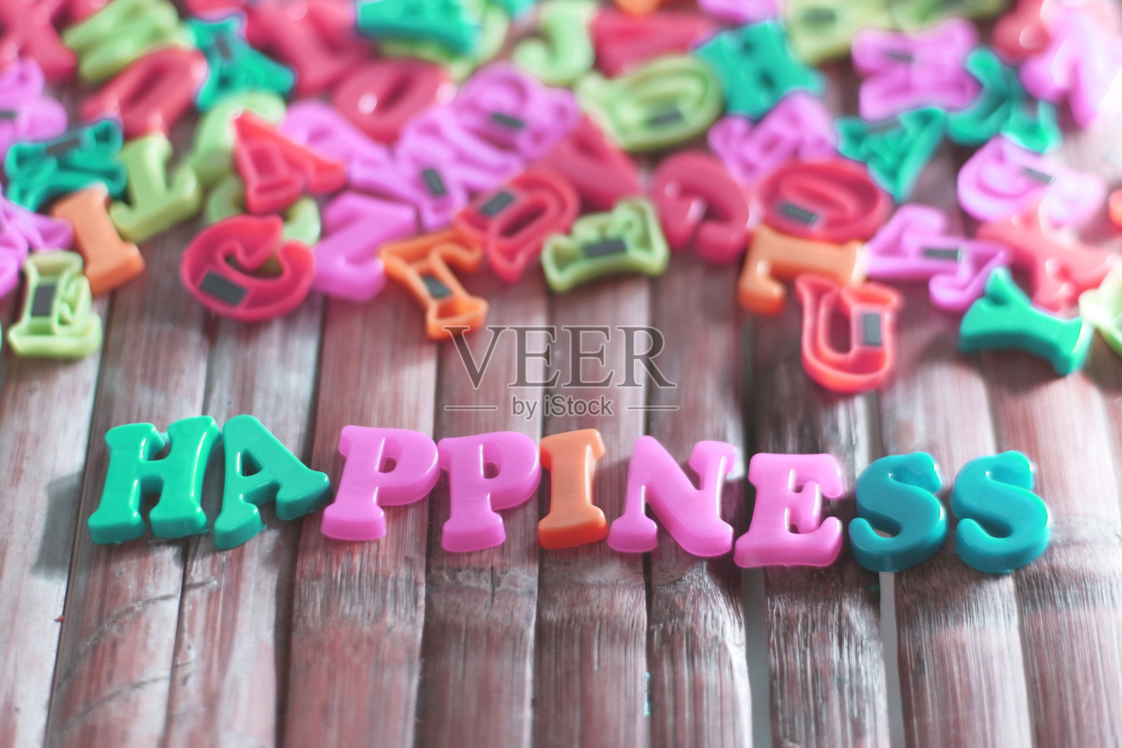 五颜六色的塑料字母在木质表面拼写出“happiness”照片摄影图片