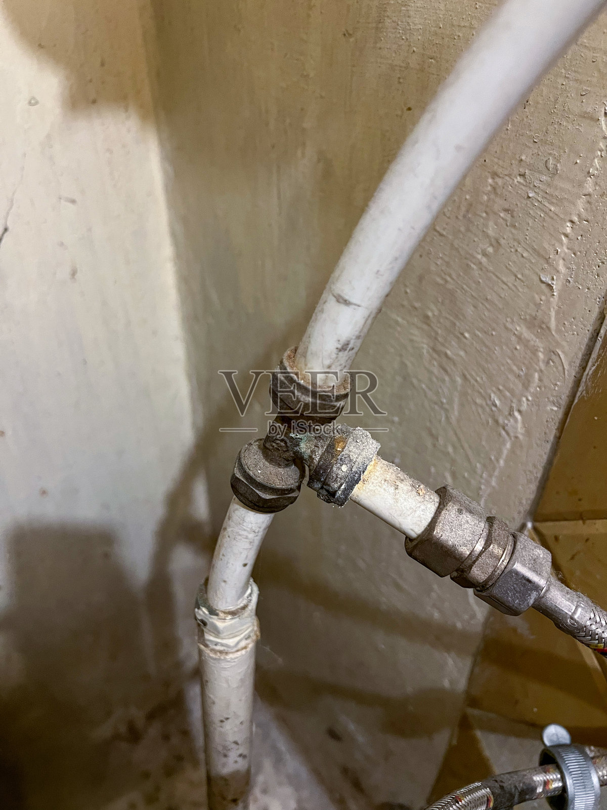 生锈的管道和漏水三通接头特写。家庭供水系统维护问题。照片摄影图片