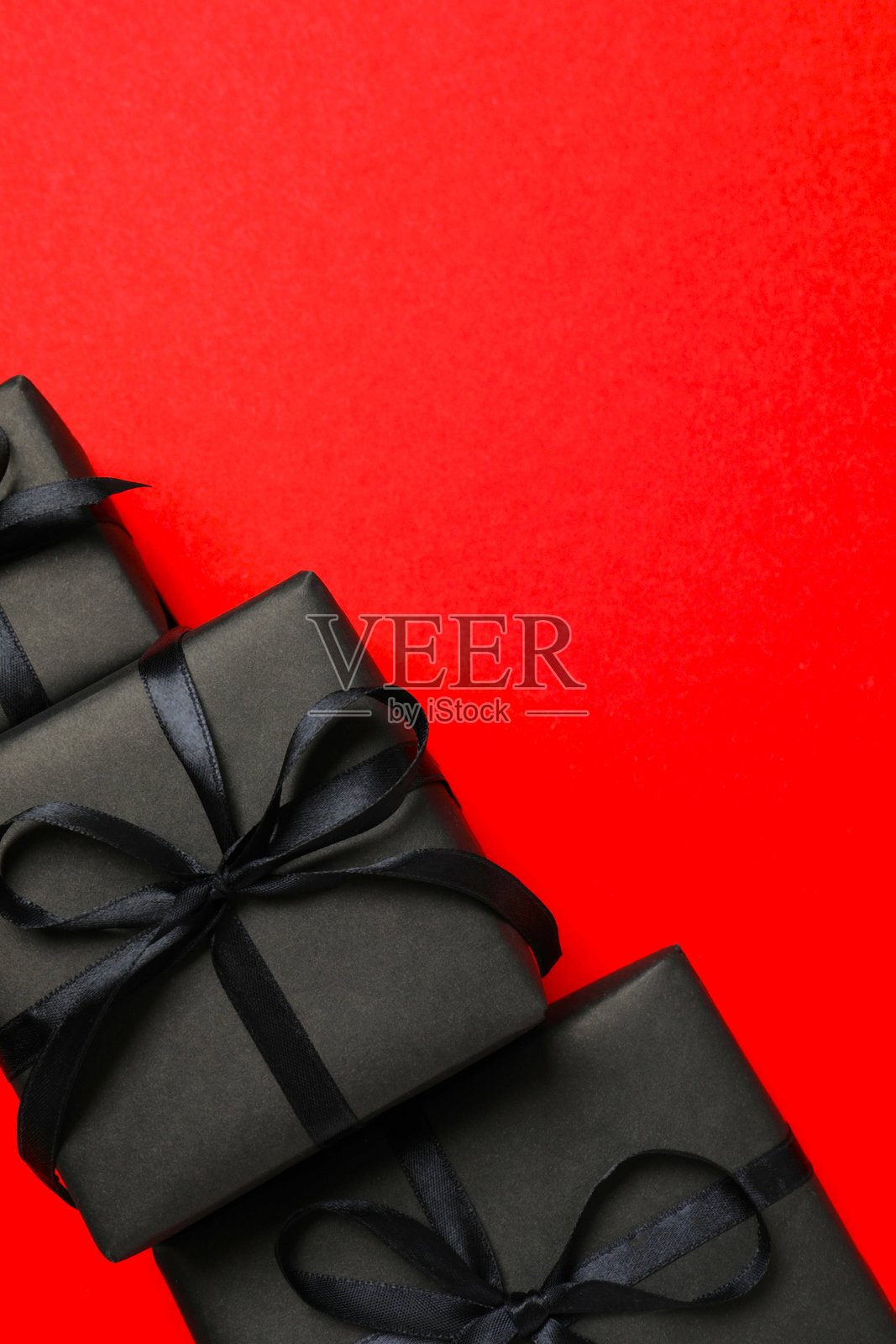 黑色星期五概念。礼品盒系着丝带，背景为红色，可供您添加信息或促销信息。照片摄影图片